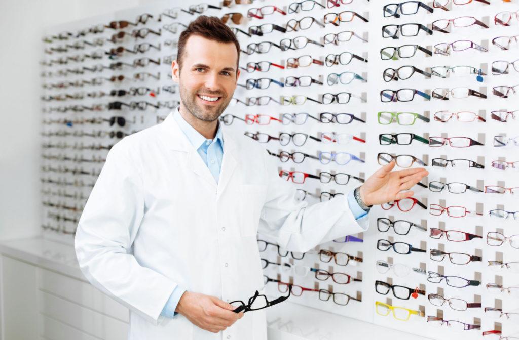 A male optometrist is showing all the kinds of eye glasses they have available.