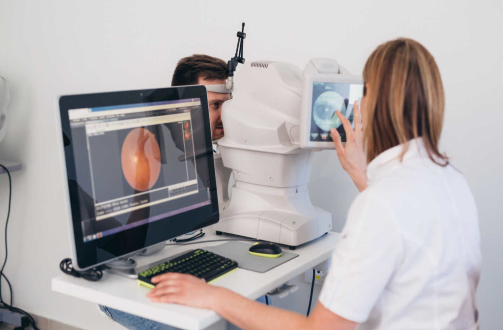 A woman performing an eye scan on a male patient during a comprehensive eye exam