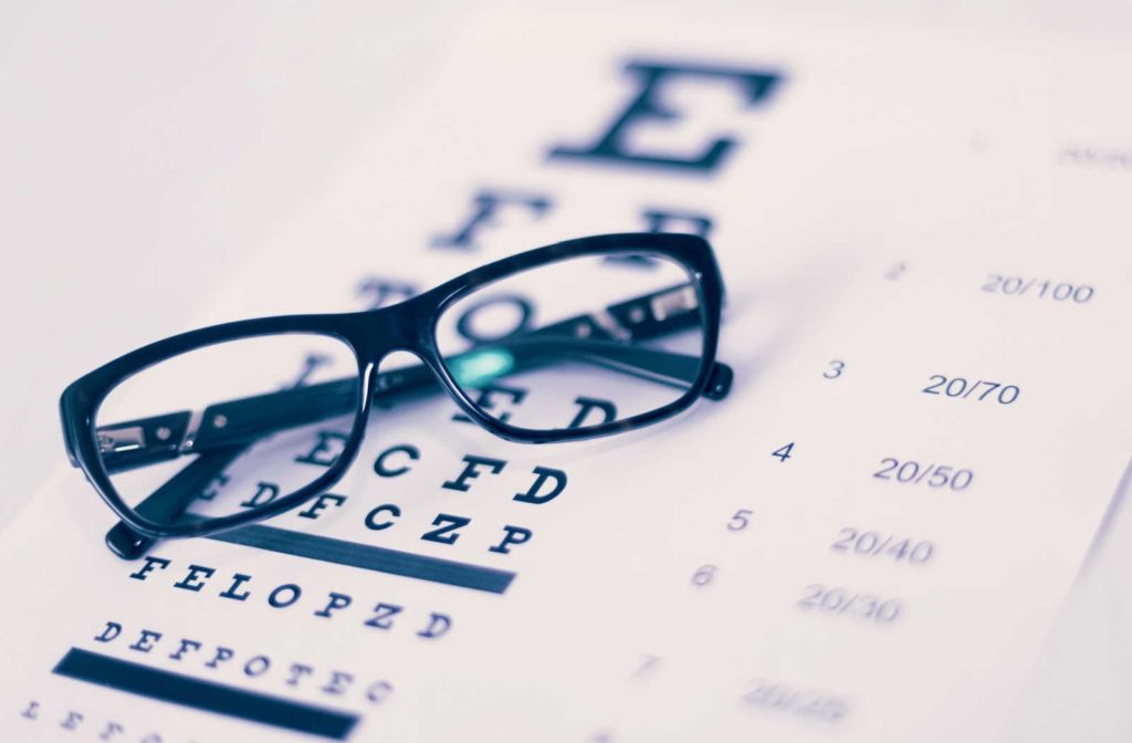 Glasses sitting on top of an eye chart used to test visual acuity