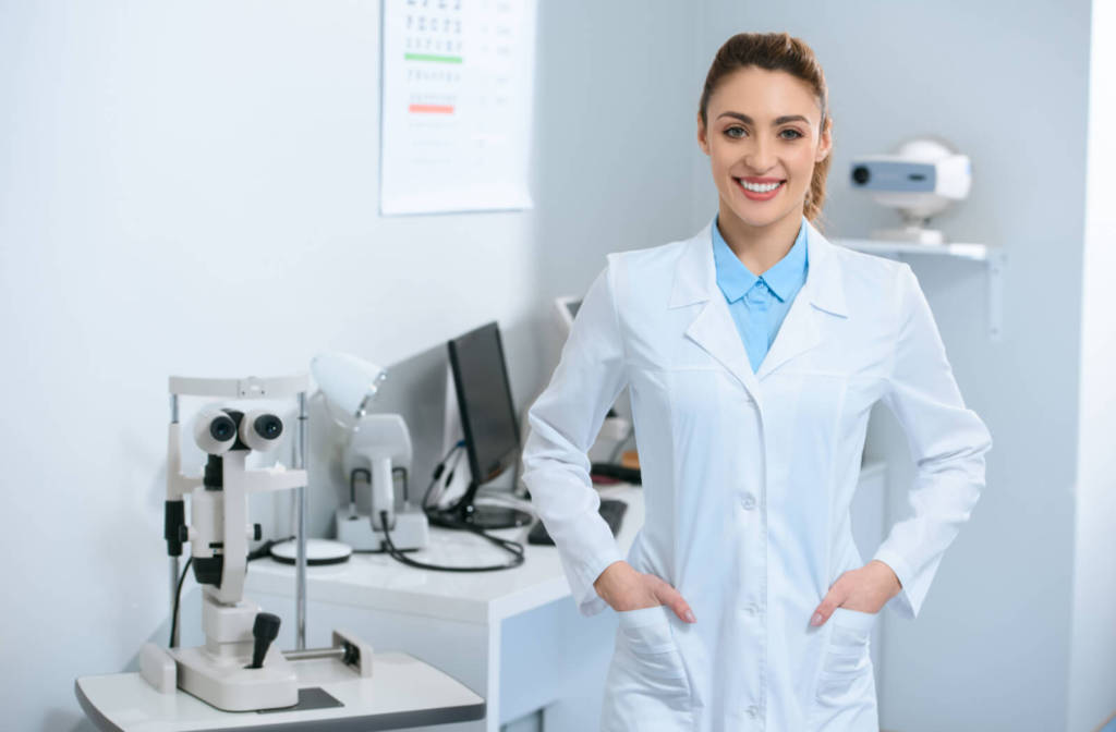 A female optometrist smiling with medical equipment in the background.