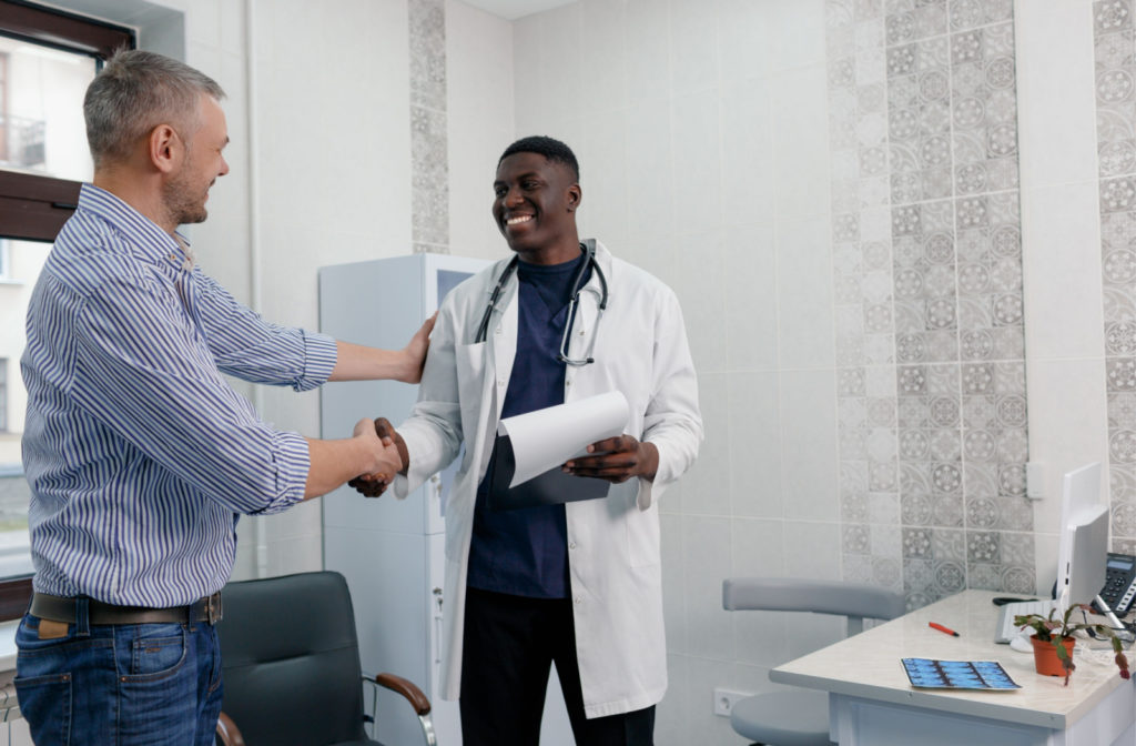 A businessman smiling and shaking hands with an optometrist.