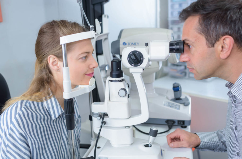 A male optometrist using a medical device to examine the eyes of a female patient and look for potential eye problems.