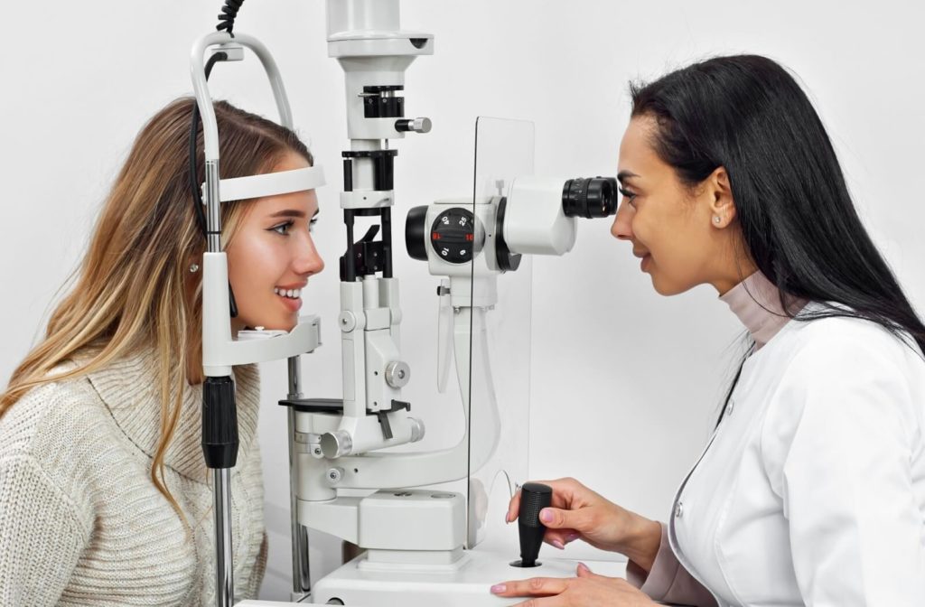 A patient is receiving an eye exam from an optometrist who is using a slit lamp to examine her eyes.