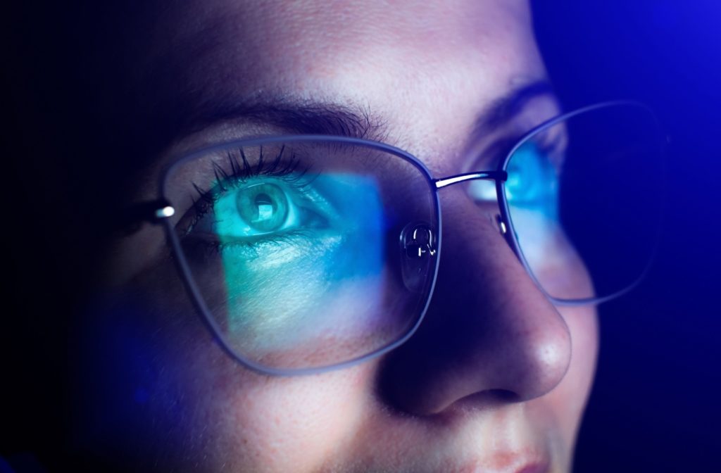 A close-up of a woman's eyes behind glasses designed to protect against blue light and screen glare while working at a computer.