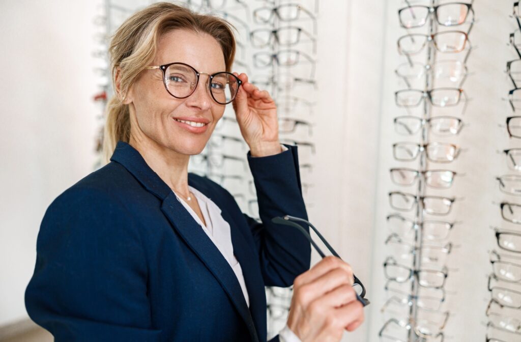A professional woman tries on different eyeglass styles at her optometrist's office.