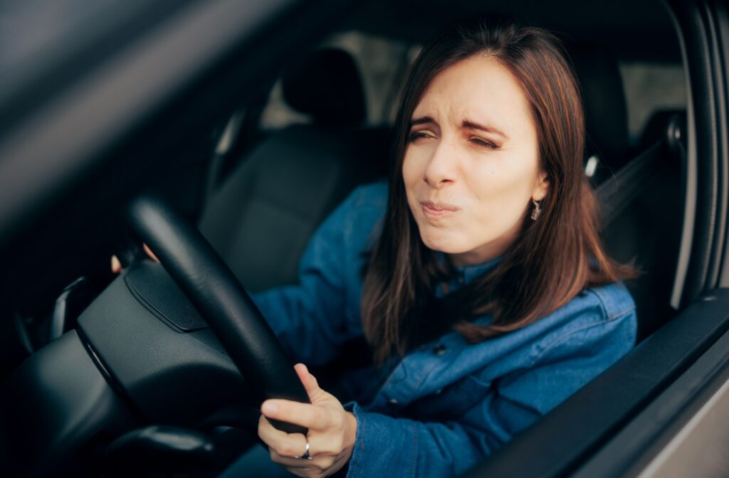 A person with myopia sitting in a car and squinting to see a sign in the distance.