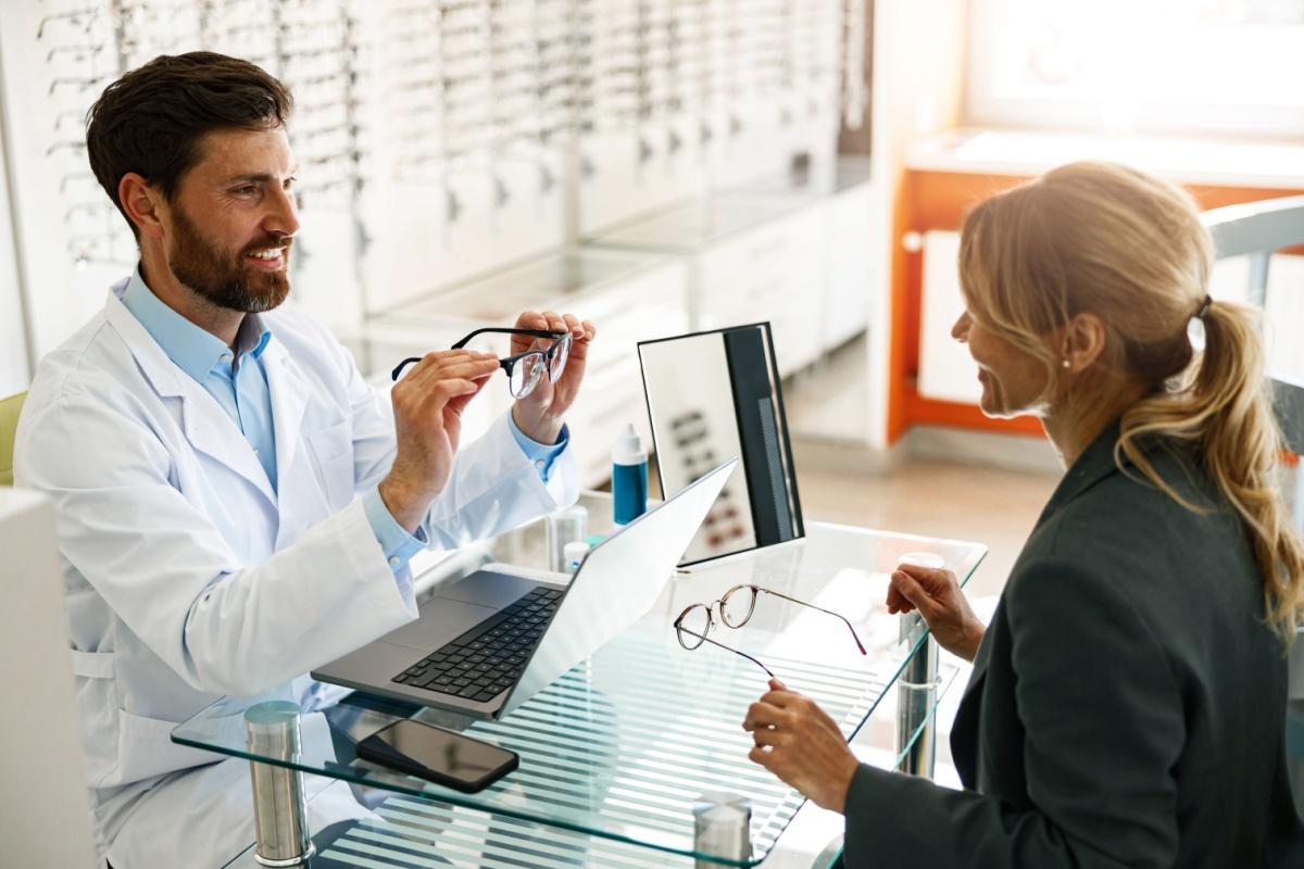 An optician helping a patient choose and fit their glasses properly after an eye exam.